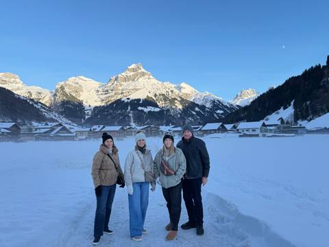       Group in front of snow-covered mountains and village houses.
  