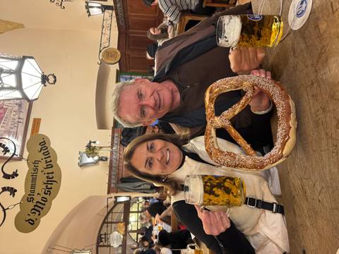       Couple inside a restaurant holding a pretzel and beers.
  