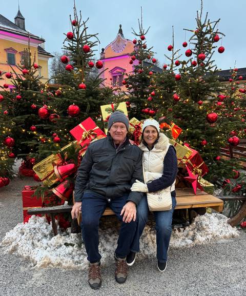       Couple sitting in front of Christmas decorations.
  