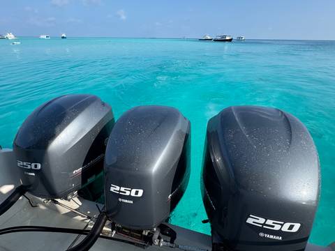       Close-up of three large outboard motors over turquoise water.
  