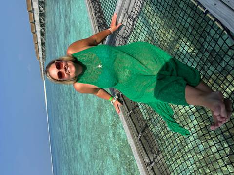       Person sitting on a net over water with a clear blue sea background.
  