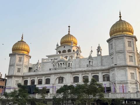 A Sikh temple with golden domes against a clear sky.