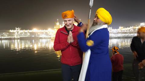 Two men in traditional attire posing by a lake at night.
