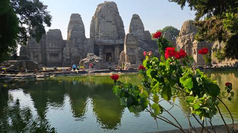 Historic stone structures with a pond and flowers in foreground.