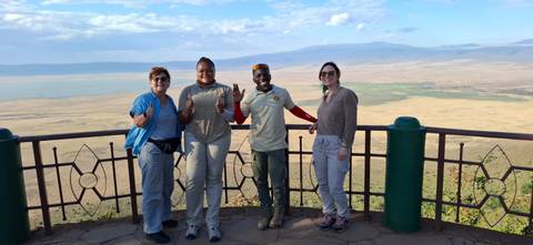 Four people posing on a viewpoint overlooking a vast landscape.