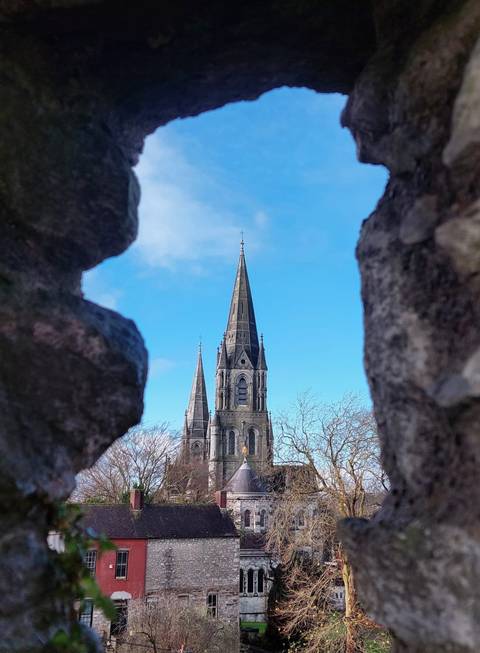 Gothic cathedral spires viewed through stone opening.