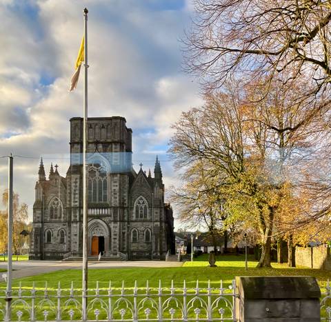 Church with a flag and trees in front.