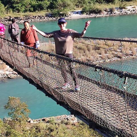Person walking on a suspension bridge over a river.