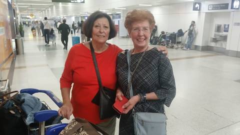 Two women smiling in an airport terminal.