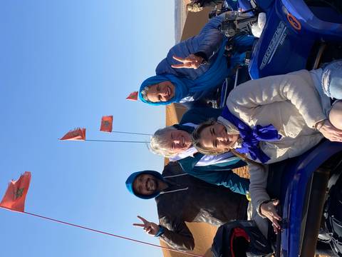 Group of tourists with Moroccan flags in a desert.