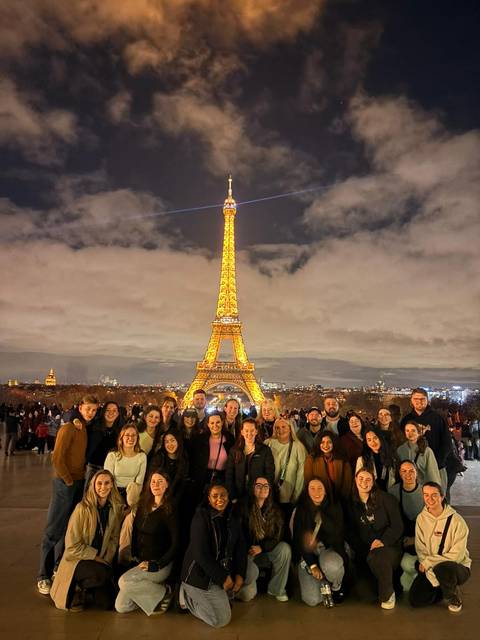 Large group in front of the illuminated Eiffel Tower.