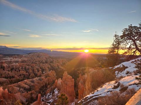 Sunset view of Bryce Canyon National Park with snow and rock formations.