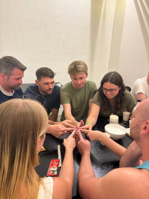Group of people sitting around a table, playing a group game.