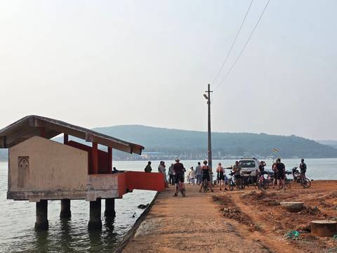Group of people with bicycles near a lake and mountains.