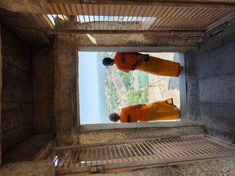 Two people standing by a stone window enjoying a panoramic view.