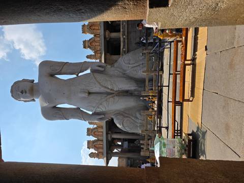 Massive stone statue of a standing figure in an open courtyard.