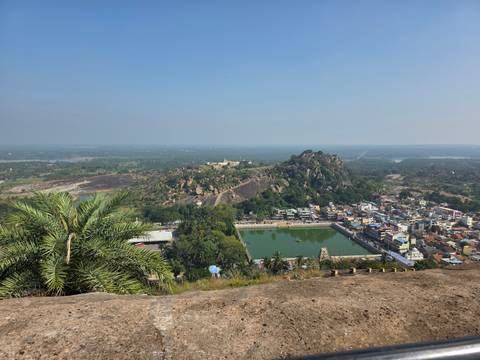 Aerial view of a rocky hill with structures and lush greenery.