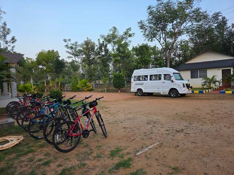A small bus next to a row of bicycles in a forested area.