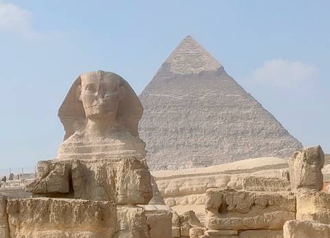       A famous ancient Egyptian sphinx and pyramid under a blue sky.
  