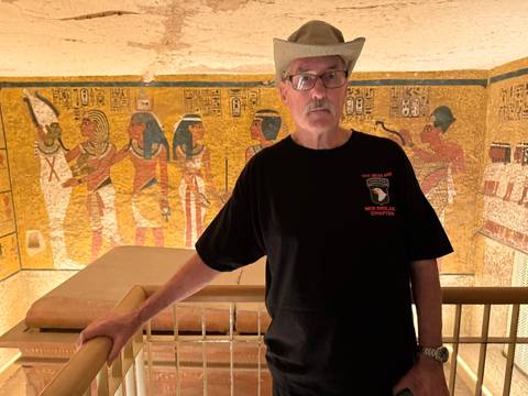 Tourist inside a decorated tomb with wall art.