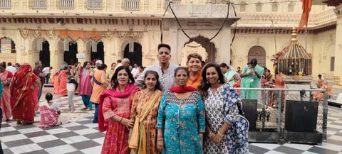       Group of people in traditional clothing posing in a temple courtyard.
  