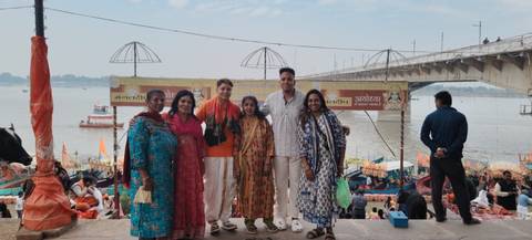       Group of people posing by a river with a bridge in the background.
  