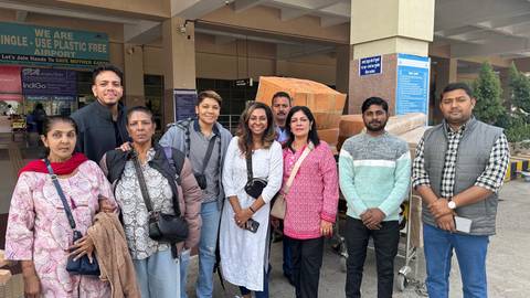       Group of people posing outside an airport.
  