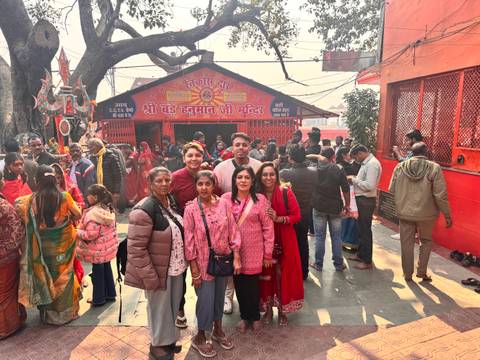       Group of people posed in front of a busy religious site.
  