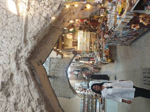       Tourists walking through a market with various goods on display.
  