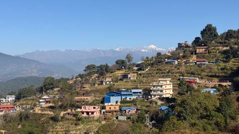       Hillside village with colorful houses and mountain backdrop.
  