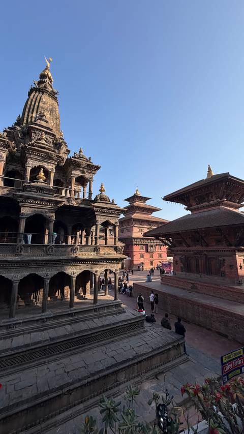       Traditional buildings in a historic square with people around.
  