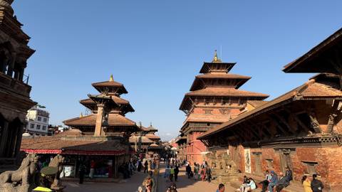       Historic square with temples and people moving around.
  