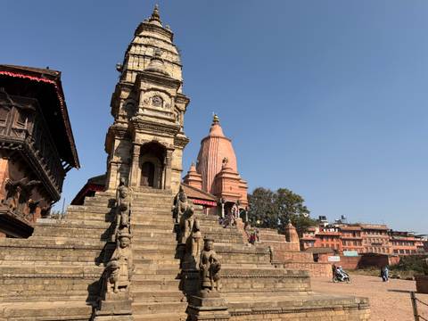       Temple complex with multiple spires and people walking up steps.
  