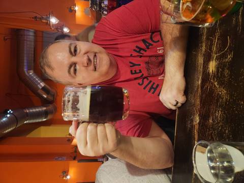       Man holding a beer mug in a lively bar setting.
  