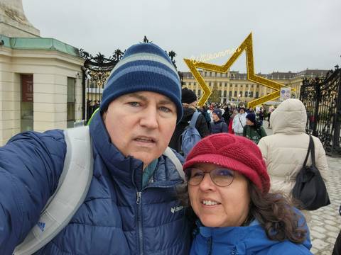       Couple posing in front of a historic building decorated for Christmas.
  