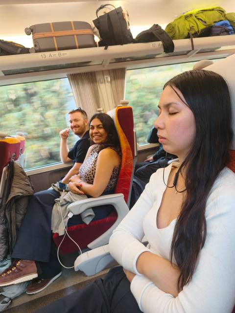 People sitting on a train, some smiling and one asleep.
