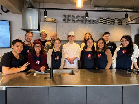 A group of people with a chef in a kitchen setting.