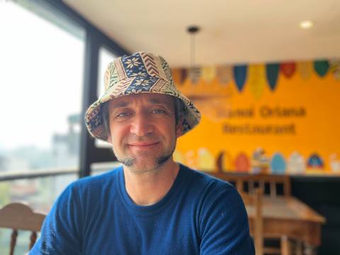A person wearing a patterned hat and a blue shirt inside a restaurant.