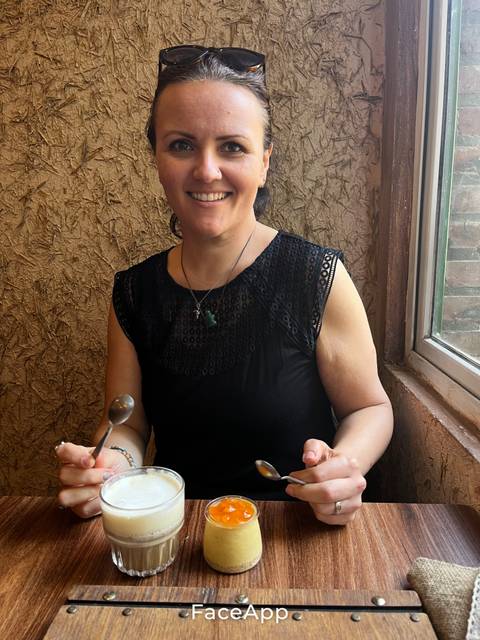 A woman smiling with a dessert in hand.