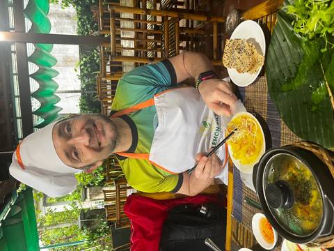A person in a chef hat enjoying a meal with chopsticks.