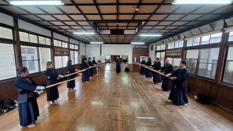 Group of people practicing martial arts with wooden swords.