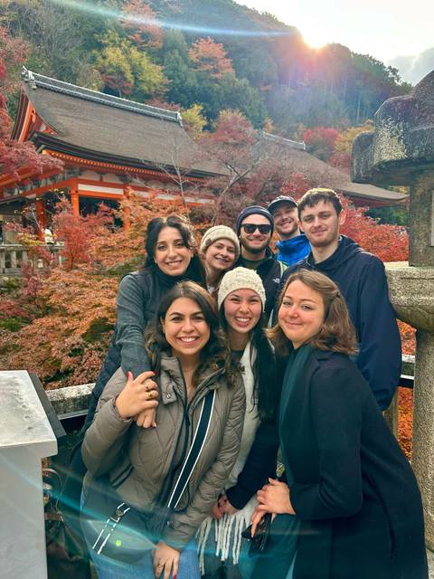 Group of people with autumn leaves and a temple.