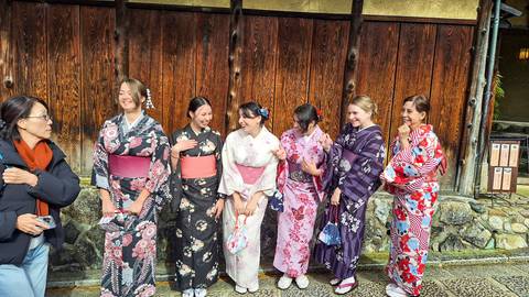       People in traditional Japanese kimonos standing outside.
  