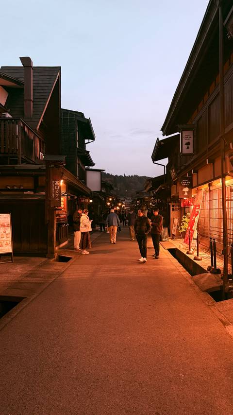 People walking in a traditional Japanese street at dusk.