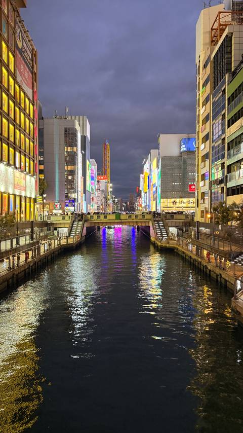 Vibrant cityscape at night with reflective water canal.