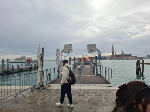 Tourist on a dock with a view of Venice across the water.