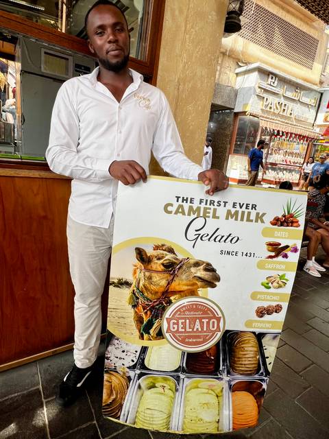       Person holding a sign advertising camel milk gelato.
  