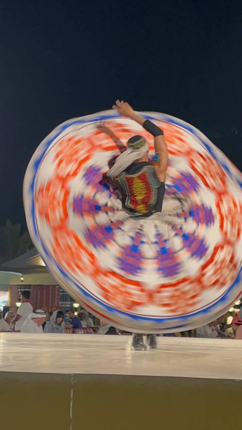       Blurred motion image of a person in a colorful costume spinning.
  