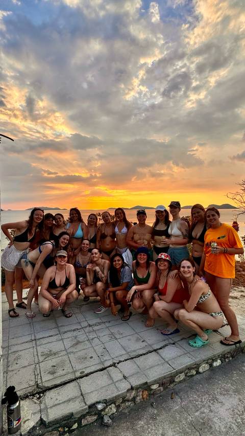 Group of people posing with sunset in the background.