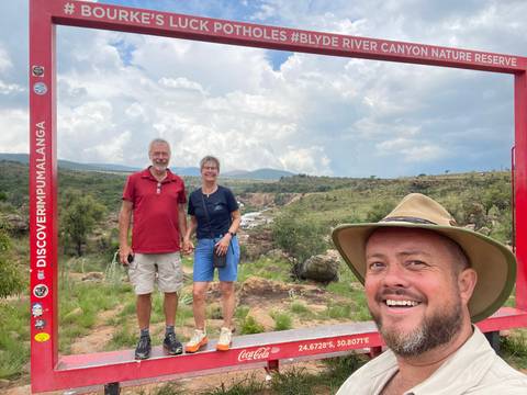       Group of people posing with natural landscape in the background.
  